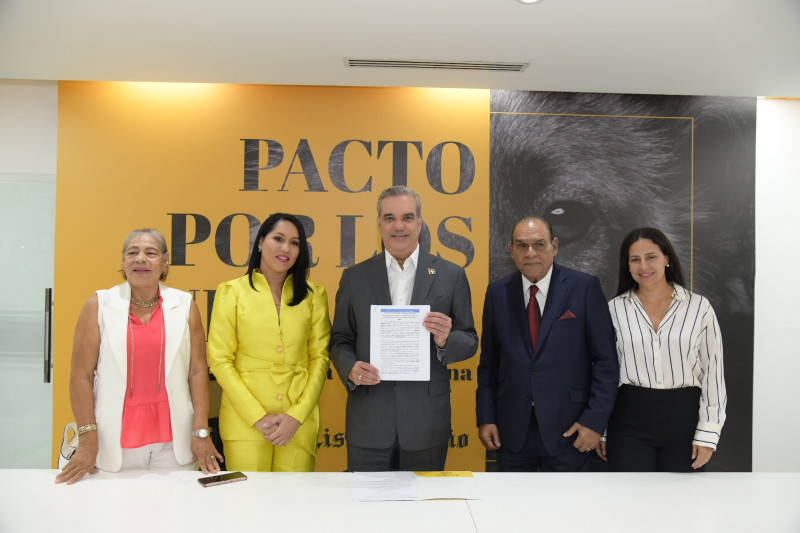 El presidente Luis Abinader (centro) muestra el pacto luego de firmarlo.