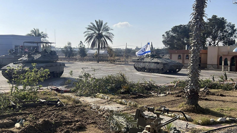 En esta imagen, proporcionada por las Fuerzas de Defensa de Israel, un tanque con una bandera israelí entra al lado gazatí del paso fronterizo de Rafah, el 7 de mayo de 2024.