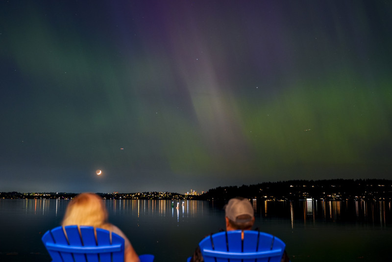 Un grupo de personas admira la aurora boreal que ilumina el lago Washington