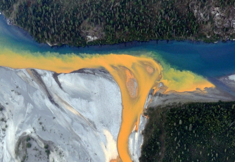 Una vista aérea del río Kutuk en el Parque Nacional Puertas del Ártico de Alaska que parece pintura naranja derramándose en el agua azul clara.