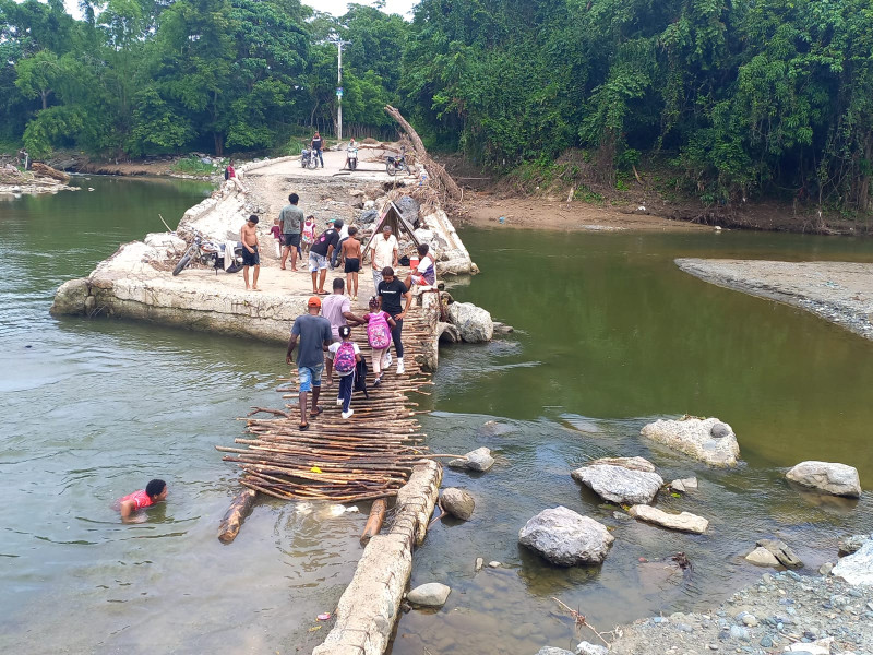 Con cada crecida del río Camú, el badén se desintegra, por lo que los comunitarios han improvisado un puente de tablitas para cruzar a pie y en motocicletas.