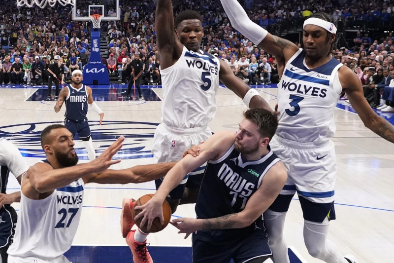 Luka Doncic es presionado por el centro Rudy Gobert , el guardia Anthony Edwards y el delantero Jaden McDaniels.