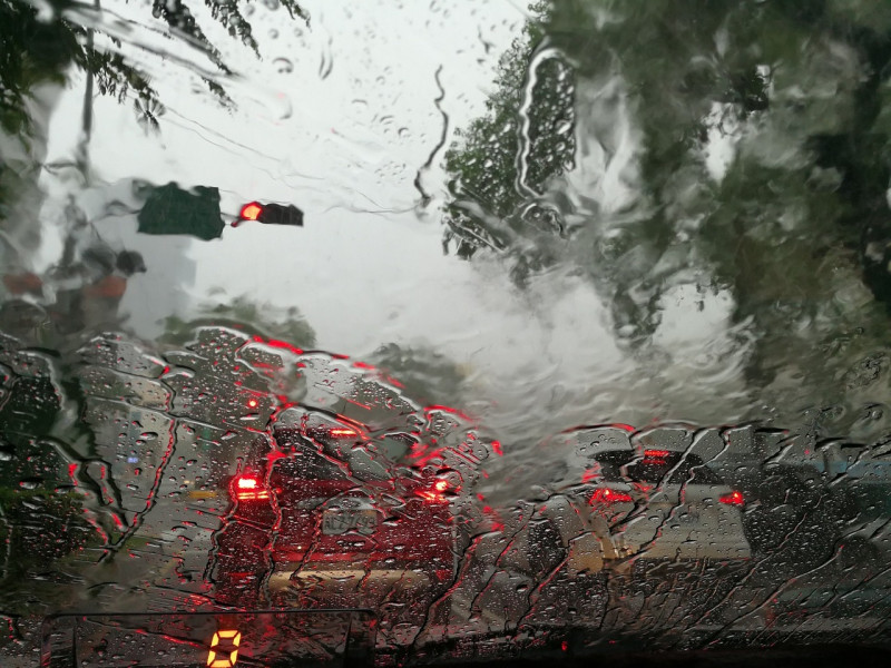Fotografía muestra lluvia cayendo en el cristal de un vehículo.