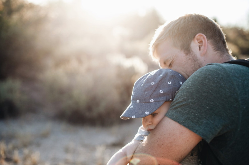 Fotografía muestra a un padre que carga a su hijo.