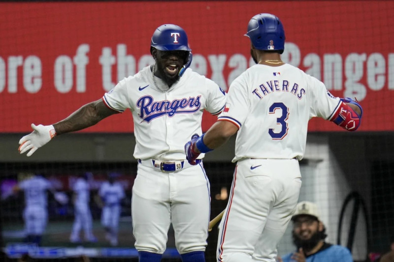 Adolis García felicita a su compañero de Texas, el dominicano Leody Taveras, quien conectó un jonrón de dos carreras en el juego del miércoles ante los Mets.