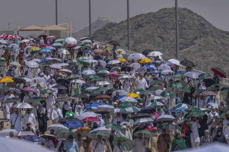 Peregrinos musulmanes usan sombrillas para protegerse del sol