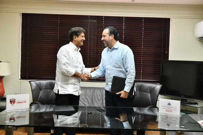 Alberto Rodríguez, del Inefi y Manuel Estrella, del Cibao FC, se saludan tras la firma del convenio.