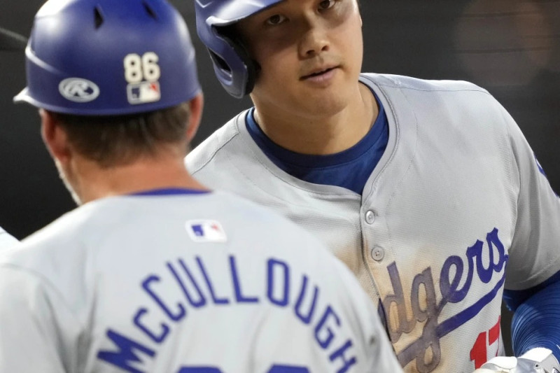 Shohei Ohtani, de los Dodgers, es felicitado por el coach de la inicial Clayton McCullough luego de pegar un sencillo productor en el juego ante los Medias Blancas.