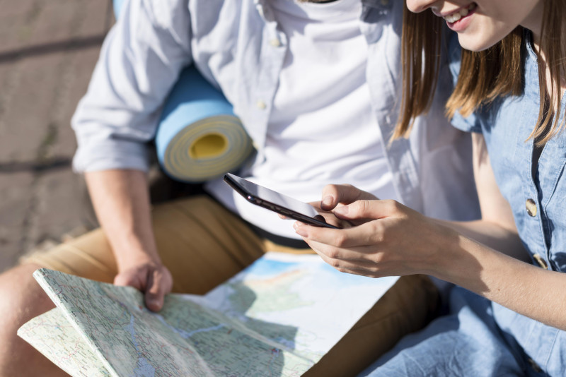 Pareja viajera con mapa en papel y en su smartphone. Foto: Freepik.