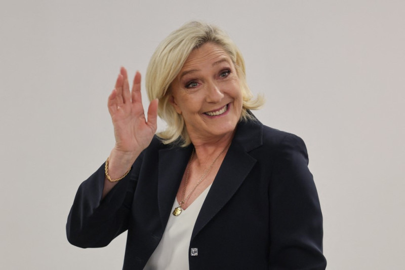 Marine Le Pen, jefa del grupo parlamentario de extrema derecha Rassemblement National (RN) en la Asamblea Nacional, saluda antes de entrar en una cabina para marcar su voto