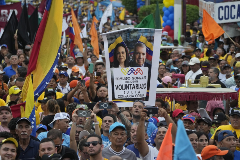 Un partidario muestra un cartel con las imágenes de los líderes de la oposición María Corina Machado y Edmundo González durante un acto de campaña en Maracaibo, Venezuela, el jueves 2 de mayo de 2024