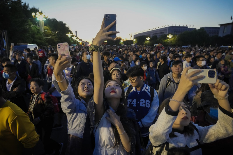 Varias personas toman fotografías con sus teléfonos en una calle cercana a la plaza de Tiananmén, el domingo 1 de octubre de 2023, en Beijing, China.