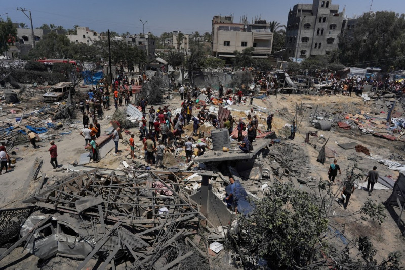 Palestinos observan la destrucción resultante de un ataque militar israelí contra el campo de desplazados internos de Al Mawasi, cerca de la ciudad de Jan Yunis, en el sur de la Franja de Gaza, el 13 de julio de 2024