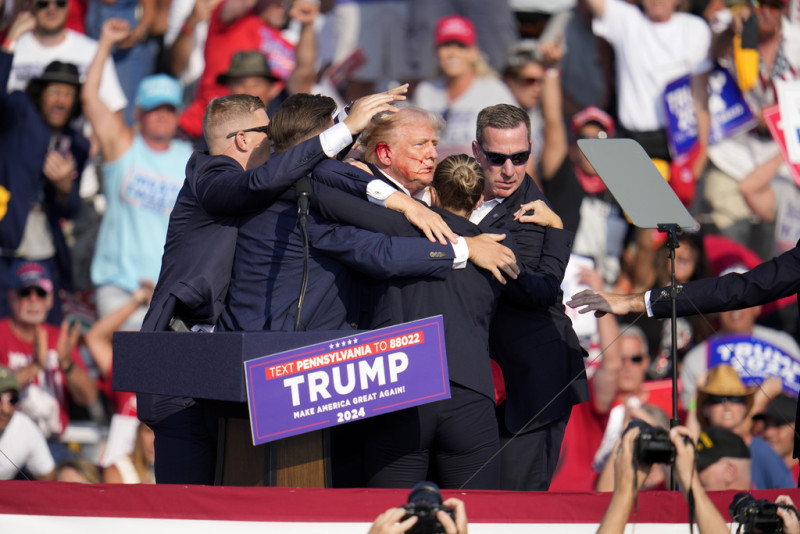 El candidato presidencial republicano, el expresidente Donald Trump, recibe ayuda para bajar del escenario en un evento de campaña en Butler.