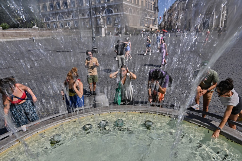 La gente se refresca en la fuente de los Leones en la Piazza del Popolo en Roma