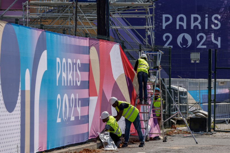 Los trabajadores arreglan pancartas de París 2024 en el centro de la ciudad de París el 17 de julio de 2024, antes de los Juegos Olímpicos y Paralímpicos de París 2024.