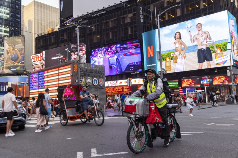 Sergio Solano, un inmigrante de México, pasea en bicicleta por Times Square mientras realiza una entrega, el 21 de junio de 2024, en Nueva York.