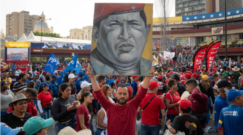 Un simpatizante de Nicolas Maduro sostiene un cuadro con la imagen de Hugo Chavez delante del Consejo Nacional Electoral (CNE) el 25 de marzo de 2024.