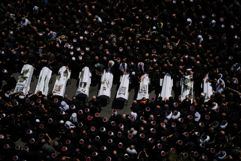 Dolientes de la minoría drusa rodean los cuerpos de algunos de los 12 niños y adolescentes asesinados en un ataque de cohete contra un campo de fútbol en la localidad de Majdal Shams.