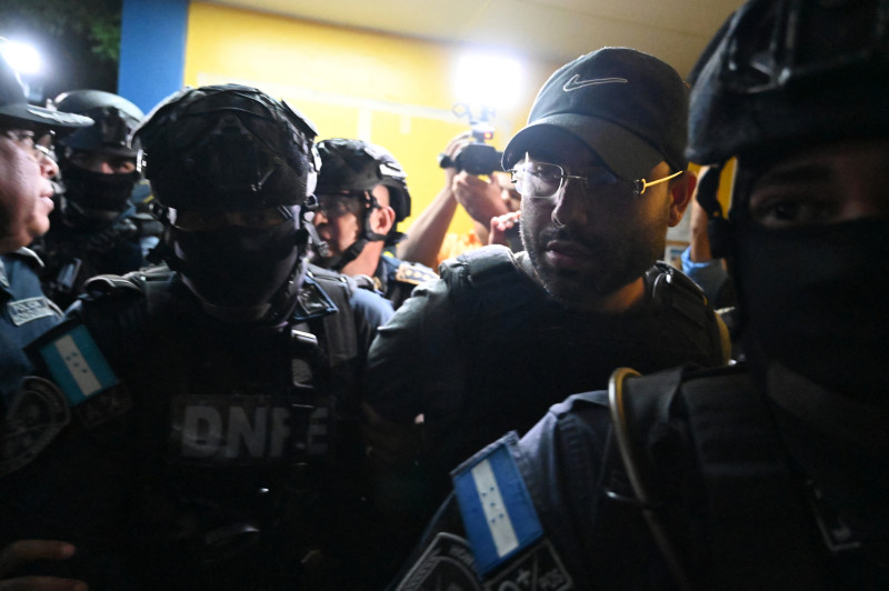 Members of the Honduran Police Special Forces Department escort the U.S. citizen Gilbert Reyes (C-R), alleged perpetrator of the murder of three women, in a police unit in Tegucigalpa on July 23, 2024. . On July 23, the Dominican Republic extradited to Honduras a U.S. citizen suspected of killing three women last January in this Central American country, which has the highest rate of femicide in Latin America. (Photo by Orlando SIERRA / AFP)