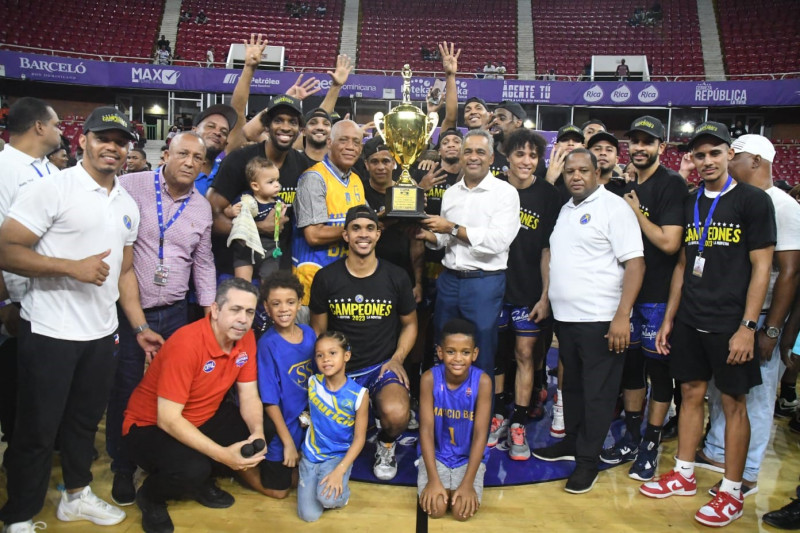 Joel Santos premia a Mauricio Báez con la copa de campeón del torneo superior distrital 2023.