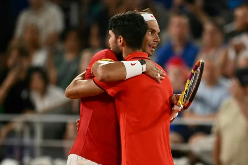 Rafael Nadal y Carlos Alcaraz se abrazan tras quedar eliminados en el torneo de dobles de París-2024.