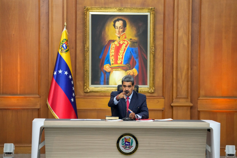 El presidente de Venezuela, Nicolás Maduro, sentado delante de una imagen del héroe de la independencia venezolana Simón Bolívar mientras da una conferencia de prensa.