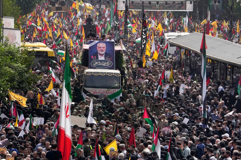 Iraníes siguen a un camión (centro) que traslada los féretros del líder de Hamás, Ismail Haniyeh, y de su guardaespaldas, que murieron el miércoles.