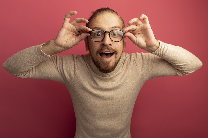 Hombre sonriente acomodándose las gafas.