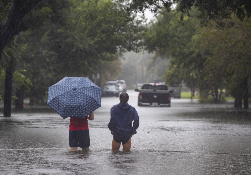 La gente se adentra en las aguas de la inundación que superan Gordon Street mientras continúa lloviendo debido a la tormenta tropical Debby, el martes 6 de agosto de 2024, en Charleston, Carolina del Sur.