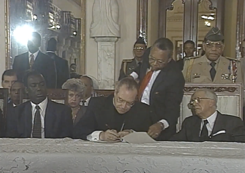 José Francisco Pena Gómez y Joaquín Balaguer observan al entonces arzobispo Metropolitano de Santo Domingo, monseñor Nicolás de Jesús López Rodríguez, cuando sienta su firma en el Palacio Nacional, como figura y testigo central del Pacto por la Democracia, el 10 de agosto de 1994.