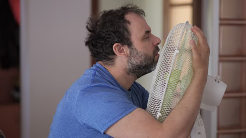 Imágen ilustrativa de un hombre abrazando un ventilador por fuerte calor.