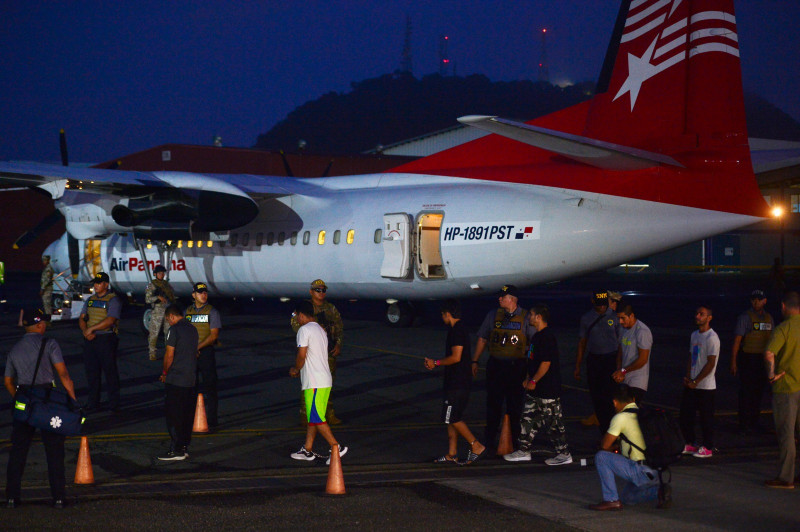 Migrantes colombianos caminan ayer esposados hacia un avión para ser deportados en el aeropuerto Marcos A. Gelabert de Albrook.