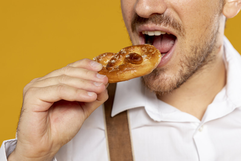 Primer plano de la boca de un hombre a punto de ingerir una sabrosa galleta. Foto Freepik.