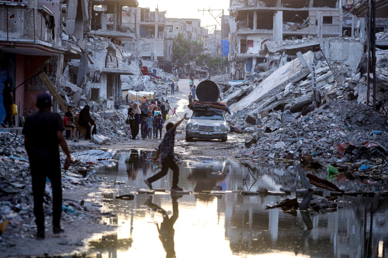 Palestinos desplazados por la ofensiva terrestre y aérea de Israel en la Franja de Gaza caminan cerca de aguas residuales en las calles del poblado de Jan Yunis, en la Franja de Gaza, el 4 de julio de 2024.