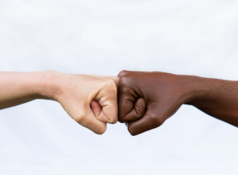 Fotografía muestra dos manos de diferentes colores raciales, golpeándose entre sí, expresando victoria. El concepto de acabar con el racismo.