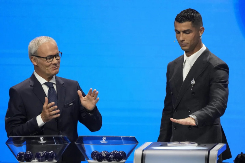 Giorgio Marchetti de la UEFA observa a Cristiano Ronaldo oprimir un botón para iniciar el sorteo de la Liga de Campeones, el jueves 29 de agosto de 2024, en Mónaco.