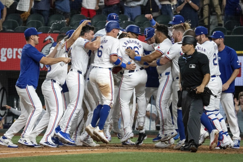 Wyatt Langford (36), de Texas, celebra con sus compañeros en el plato después de conectar un grand slam ante el relevista de los Yankees, Clay Holmes, en la novena.