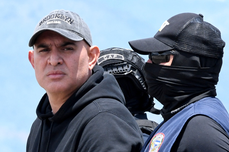 El presunto narcotraficante hondureño Mario José Calix, alias "El Cubeta", es escoltado por miembros de la Dirección Nacional de Fuerzas Especiales (Cobras) durante su extradición a Estados Unidos.