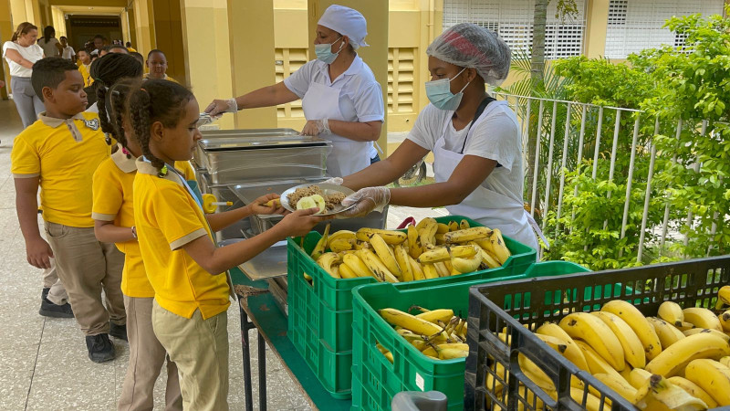 Fotografía muestra estudiantes recibiendo desayuno escolar.