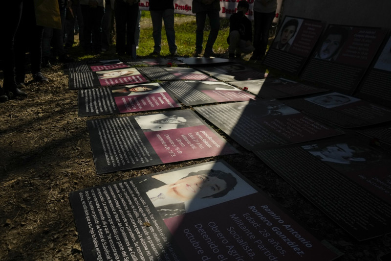 Activistas y parientes de víctimas de la dictadura militar del general Augusto Pinochet permanecen de pie junto a afiches de personas que fueron detenidas y desaparecidas.