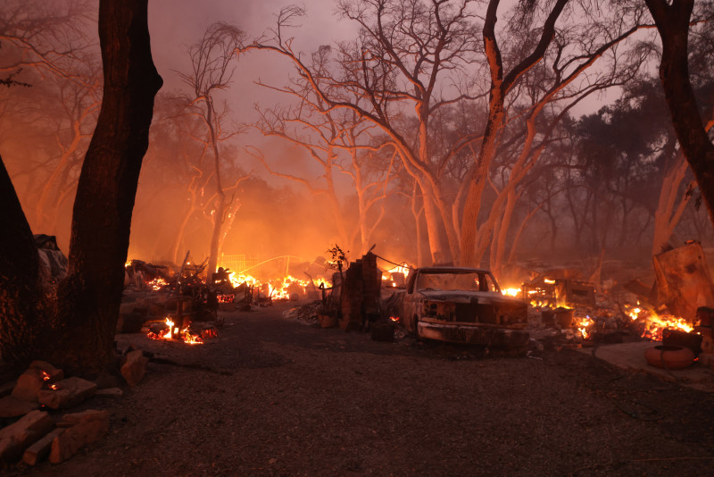 The remains of a structure burn near a burnt vehicle in El Cariso Village during the Airport Fire near Lake Elsinore, California, on September 10, 2024. - Out-of-control wildfires surrounding Los Angeles continued to grow on September 10, forcing families to evacuate and blanketing the sky with choking smoke. The fast-moving Airport Fire in Orange County has consumed more than 9,000 acres (3,600 hectares) since it was started accidentally on Monday afternoon by workers operating heavy equipment. (Photo by David SWANSON / AFP)