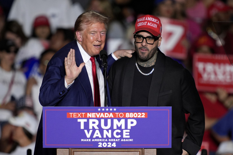 Nicky Jam habla mientras el expresidente Donald Trump, candidato presidencial republicano, escucha durante un evento de campaña en el World Market Center, el viernes 13 de septiembre de 2024, en Las Vegas. (Foto AP/John Locher)