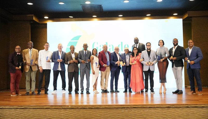 El presidente de la ACD, Américo Celado, y José Vargas junto a Yancen Pujols y otros premiados y representantes. De izquierda a derecha Orlando Méndez, Gerardo Suero Correa,  Hugo López Morrobel, Néstor García, Pedro José Mejía, Ramón Rodríguez, Beatriiz Pirón, Juan Núñez, Adelaida Hernández, William Aish, Milagros Cabral, César Marchena y Cristián Lara.