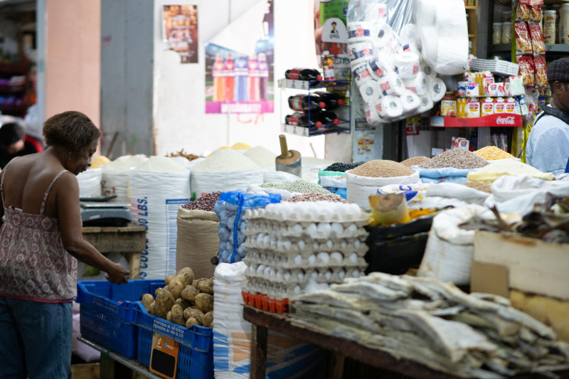 Una mujer observa una canasta de papas en un mercado del Distrito Nacional.