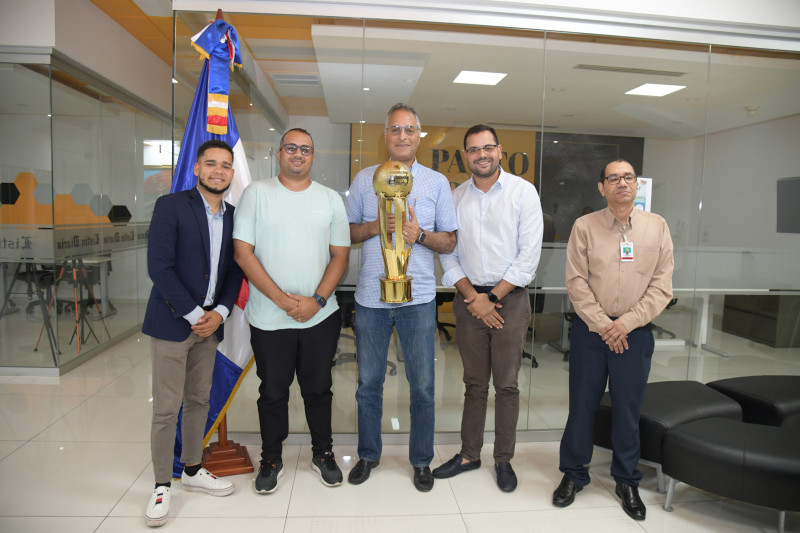 Roberto Modesto, presidente, José Modesto, vicepresidente de operaciones y Carlos de León, gerente general, posan con el trofeo junto a los redactores Moisés Mejía y Alex Rodríguez.