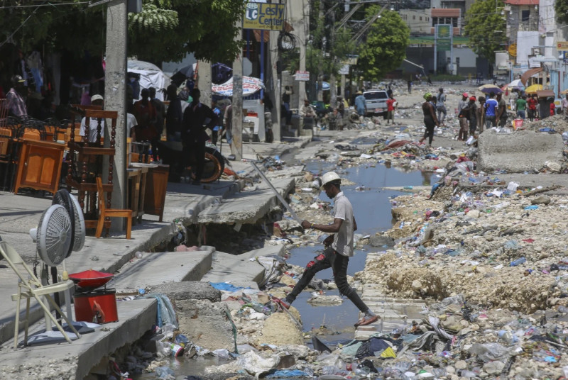 Un hombre cruza un desagüe pluvial lleno de basura en Puerto Príncipe, Haití.