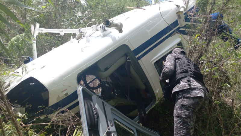 Agente policial requisa helicóptero accidentado.