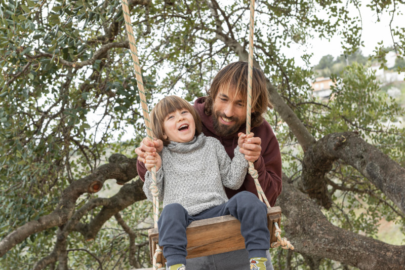 Padre columpiando a su hijo pequeño en un parque. Foto Freepik.