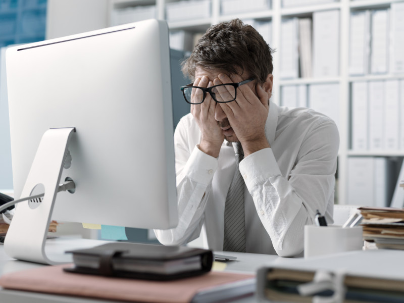 Un hombre de negocios, cansado y estresado se frota los ojos frente al ordenar de la oficina. Foto: StockPhotoPro - stock.adobe.com